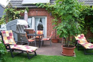 Eine Terrasse mit Gartenmöbeln, ein Ziegelhaus und ein Blumentopf.