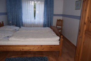 Un dormitorio con una cama de madera, una silla y una ventana con cortinas.