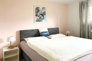 A hotel room with a bed, a nightstand, a lamp, and a painting on the wall. - Mühlenpark 1 W 3.10 "Klönschnack" (Prerow)