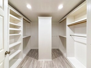 A walk-in closet with white shelving and a central pillar, wooden flooring, and a door with a brass handle. - 11327 Desert Oasis with Year-Round Pool (Apache Junction)