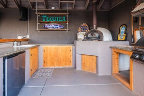 A kitchen area with a countertop, wooden cabinets, a pizza oven, a grill, and a sign that reads 'TEQUILA'. - 11327 Desert Oasis with Year-Round Pool (Apache Junction)