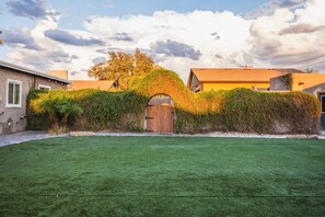Una propietat residencial amb un jardí ben cuidat, una tanca de fusta i una casa amb teulada d'àmples rajoles.
