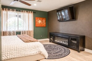 A bedroom with a bed, a television mounted on the wall, and a console table. - 11327 Desert Oasis with Year-Round Pool (Apache Junction)