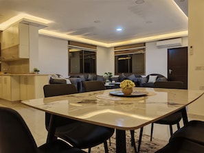 Una sala de estar moderna con mesa de comedor, sofás y zona de cocina.