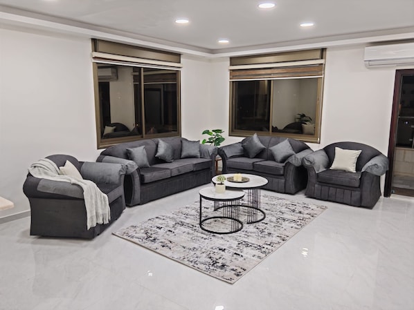 Una sala de estar moderna con un sofá modular, una mesa de centro y un ventanal grande.