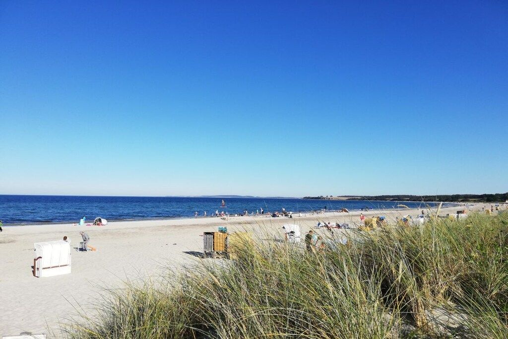 Una playa con gente, arena y mar.