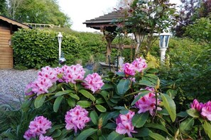 Ein Garten mit rosa Blumen und einem Pavillon.