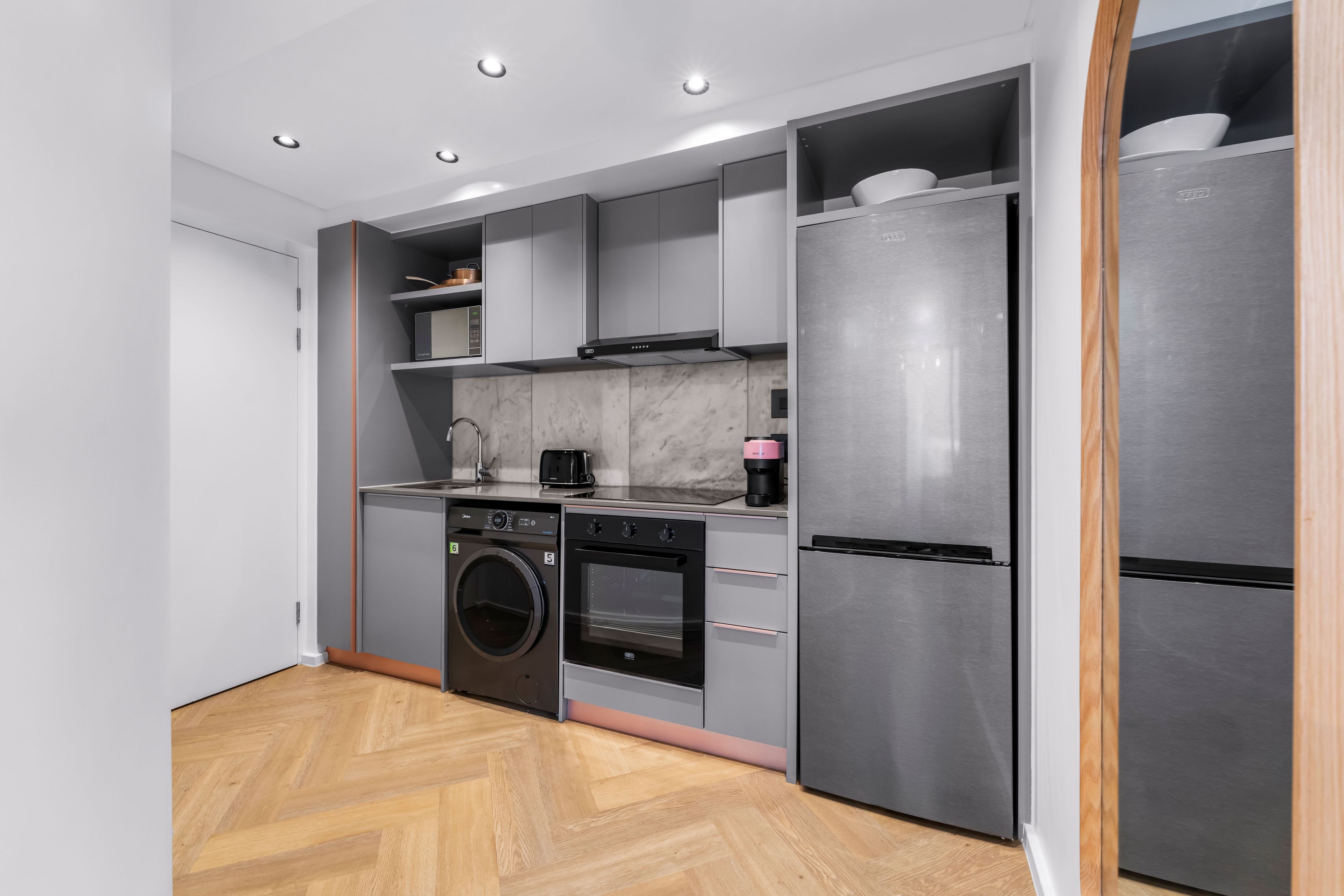 Cocina compacta equipada con lavadora, horno y un refrigerador grande.
