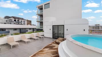 Un espace piscine sur le toit, avec des chaises longues et une terrasse en bois.