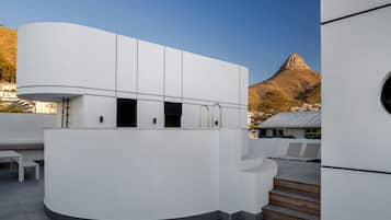 Un bâtiment moderne à la façade incurvée, avec un escalier menant à un niveau supérieur et une vue sur une montagne en arrière-plan.