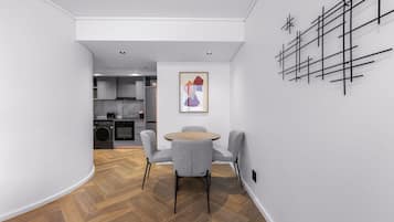 Una cocina moderna con armarios grises, una mesa de comedor de madera con sillas grises y una obra de arte abstracta negra en la pared.