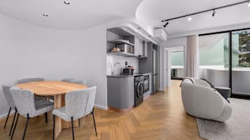 Une cuisine moderne avec un coin repas, comprenant une table ronde en bois et des chaises à revêtement gris.