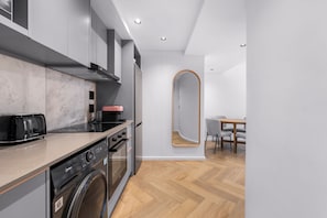 A modern kitchen with a built-in washer, a stove, and a microwave. - Apartments by Morea Sea Point (Cape Town)