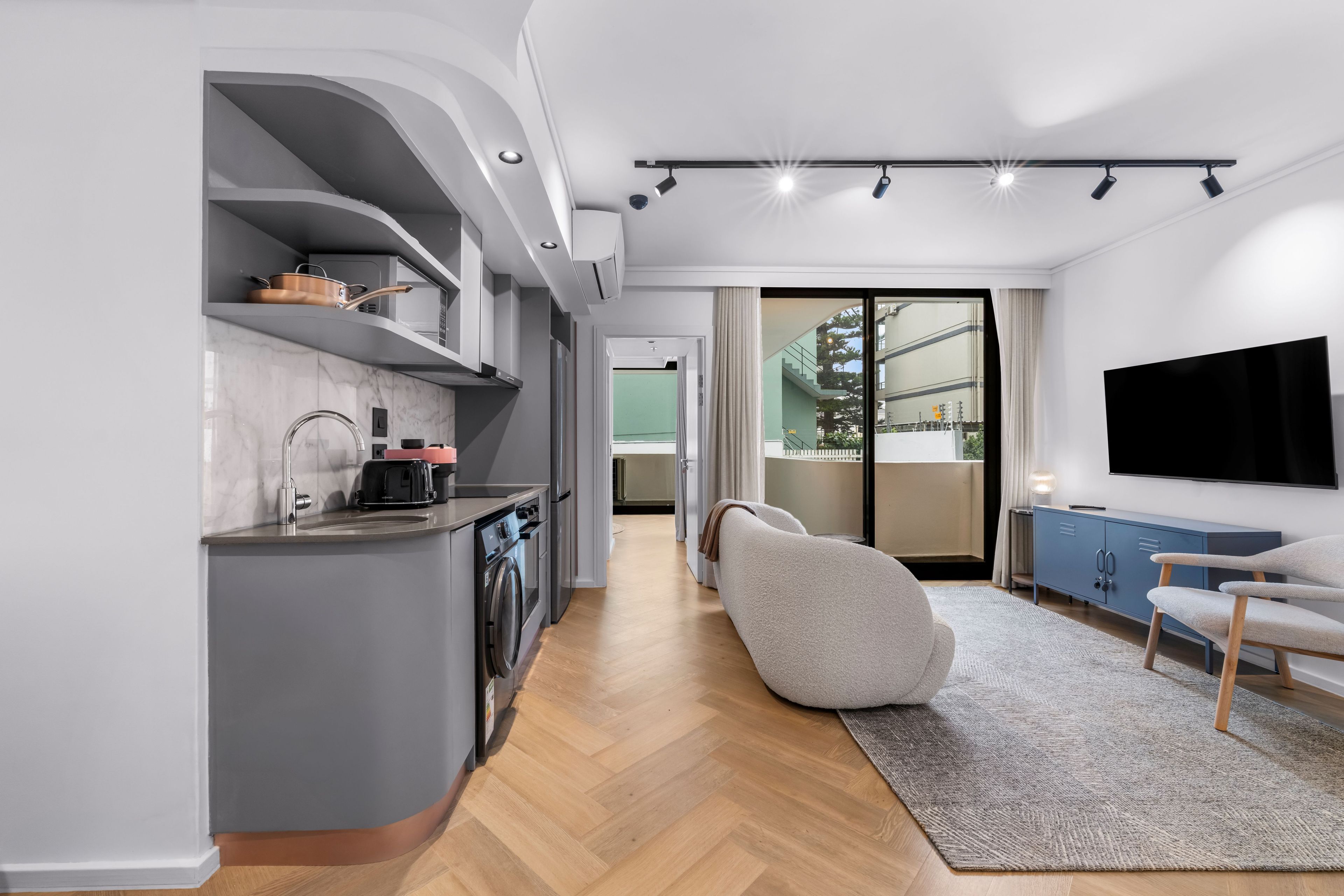 Una cocina moderna con electrodomésticos integrados, un comedor con televisor de pantalla plana y vistas al exterior.