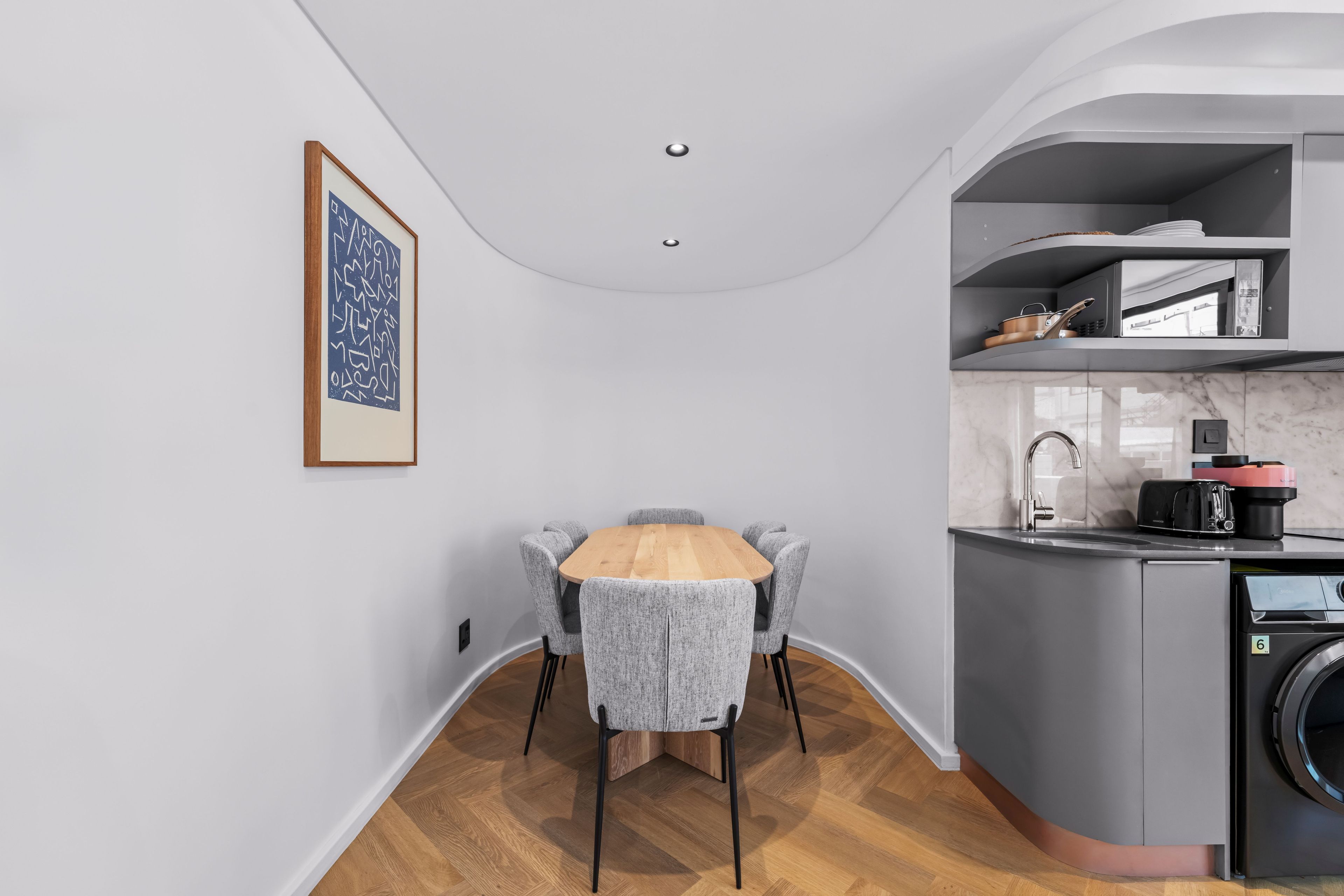 Une cuisine compacte comprenant un coin repas, un lave-linge et un petit îlot central avec un évier.