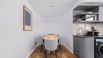 Une cuisine compacte comprenant un coin repas, un lave-linge et un petit îlot central avec un évier.