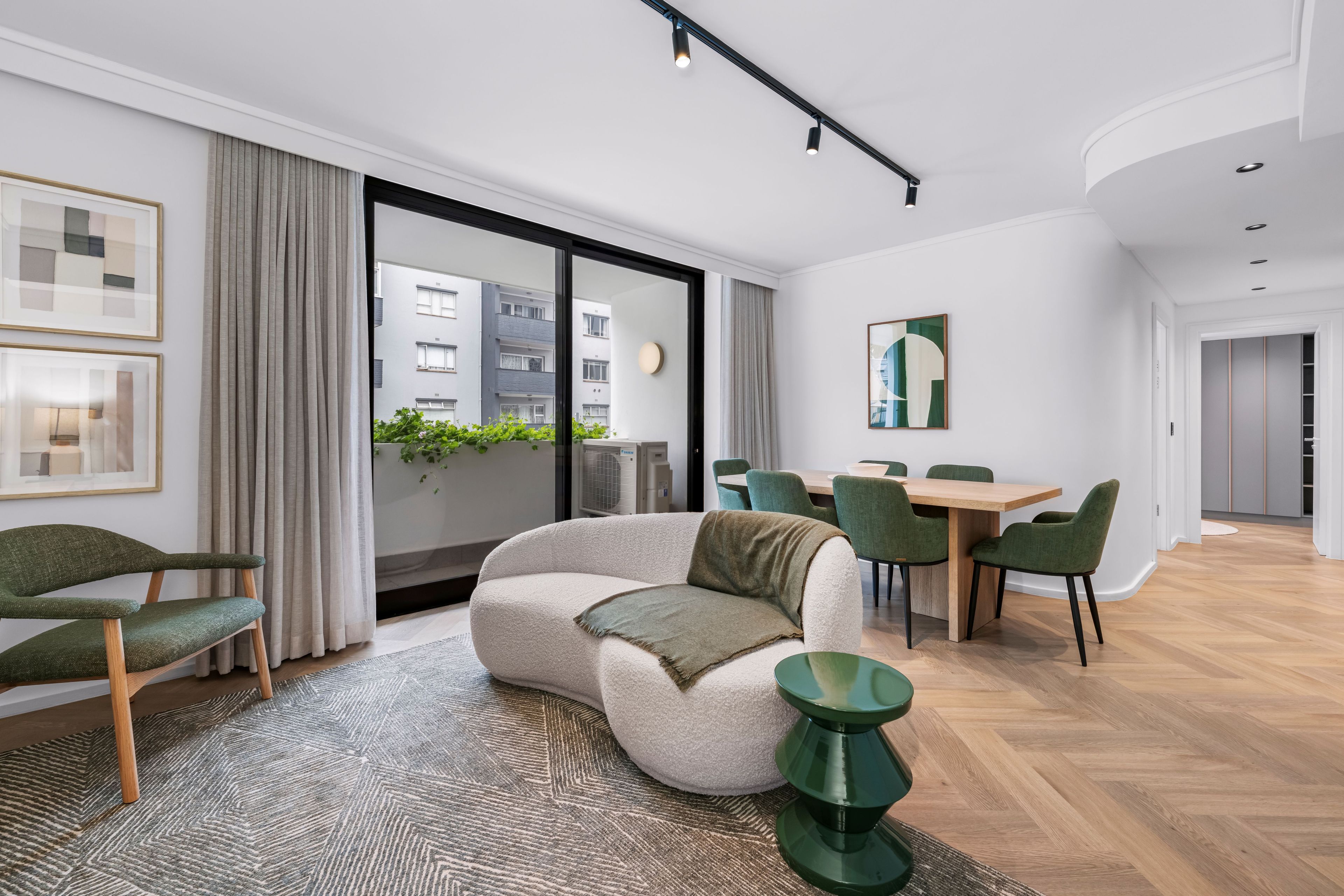 Een moderne woonkamer met een bank, eettafel, stoelen en uitzicht naar buiten.