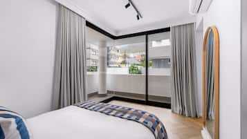Un dormitorio moderno con una cama grande, vistas al exterior y una puerta corrediza de vidrio.