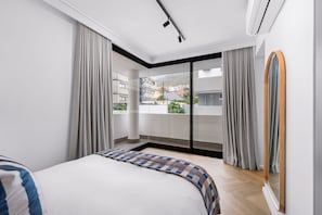 Un dormitorio moderno con una cama grande, vistas al exterior y una puerta corrediza de vidrio.