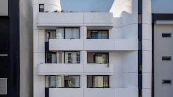 Un edificio moderno con fachada curva, varios balcones y una entrada protegida por un portón.