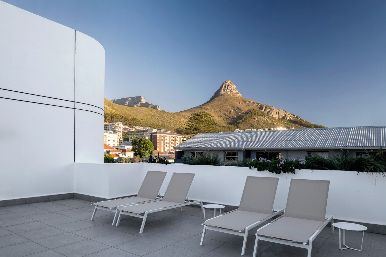 Een terras op het dak met lounge stoelen en uitzicht op een berg.