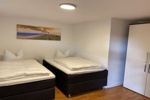 A bedroom with two beds, a wardrobe, and a painting on the wall. - Holiday apartment with 1 bedroom (Insel Poel)