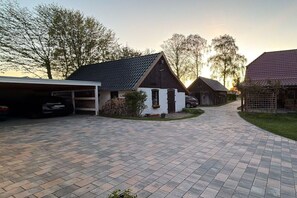 A residential driveway leading to a house with a garage, a small white building, and a red-roofed structure. - Holiday apartment with 1 bedroom (Insel Poel)