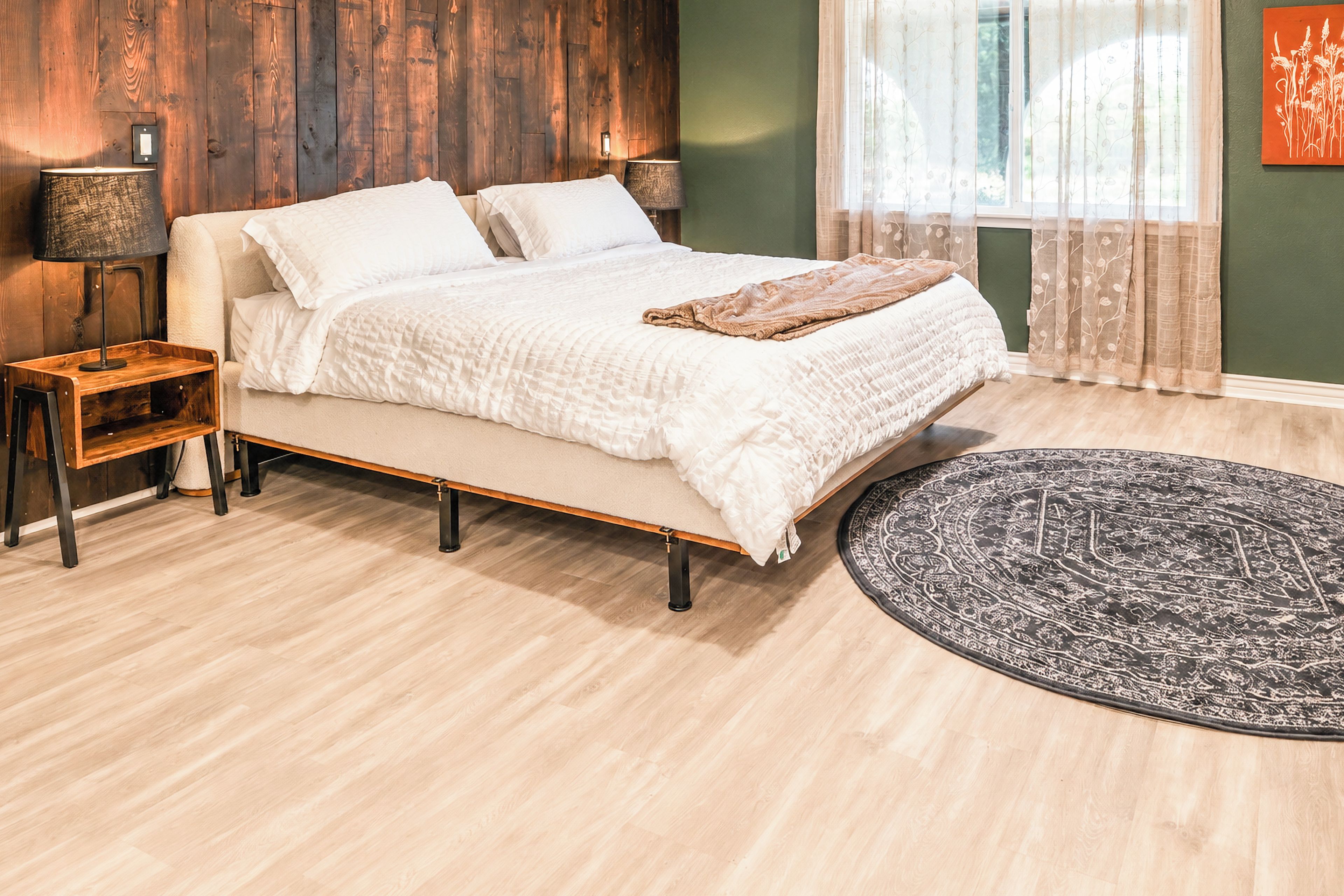 A bedroom with a bed, bedside tables, a rug, and a window with curtains.