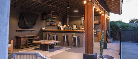 An outdoor patio area with a bar, seating, and a cactus plant.