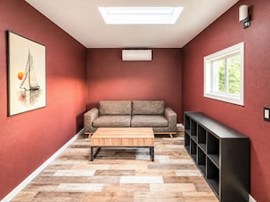 A room with a sofa, a coffee table, a TV stand, a skylight, and a framed picture on the wall. - 11327 Desert Oasis w/ Year-Round Pool (Apache Junction)