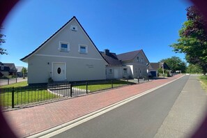 Eine Wohnstraße mit Häusern, einem gepflasterten Bürgersteig und blauem Himmel.