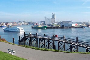 Ein Ufer mit einer Anlegestelle, Booten und einem Gebäude im Hintergrund.