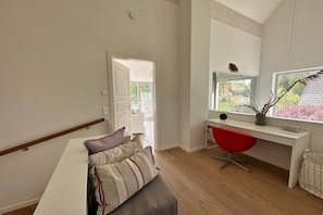 A modern room with a white desk, a red chair, a large window with a view of trees, and a bench with cushions. - "At the Old Smallholder's Farm" (Prerow)