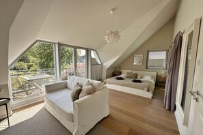 A bedroom with a sloped ceiling, a sofa, a bed, and a view of greenery outside. - "At the Old Smallholder's Farm" (Prerow)