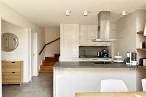 A modern kitchen with white cabinetry, a stainless steel range hood, and a built-in island with a sink. - "At the Old Smallholder's Farm" (Prerow)