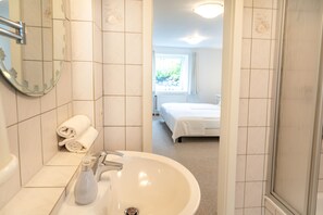 Ett badrum med handfat, spegel och handdukshängare.