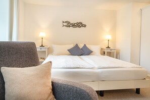 Ein Hotelzimmer mit einem Bett, zwei Nachttischlampen, einem Sessel und einer Wanddekoration.