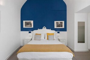 A bedroom with a white bed, blue accent wall, and two bedside tables with lamps. - A Casa di Anna (Naples)