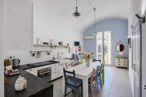 A modern kitchen with a central island, white cabinetry, and a dining area with chairs. - A Casa di Anna (Naples)