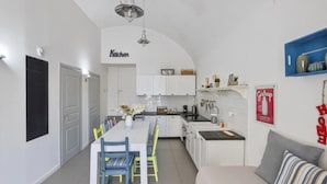 Une cuisine compacte avec des meubles blancs, une table à manger avec des chaises et un coin cuisine.