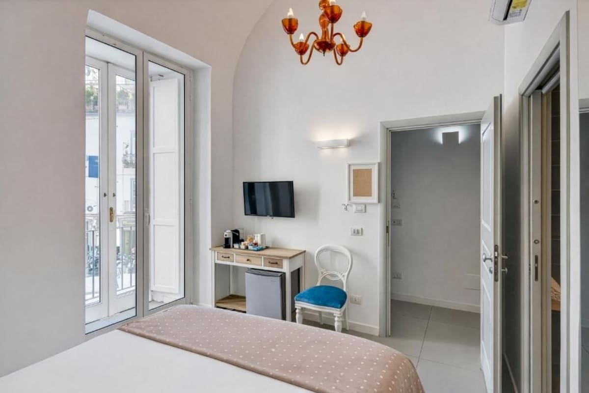 Une chambre à coucher avec un lit, un bureau, une chaise, une télévision et une porte.
