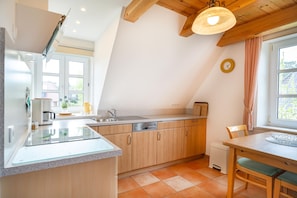 Eine moderne Küche mit einer zentralen Kochinsel, Holzschränken und einem Essbereich mit Tisch und Stühlen.