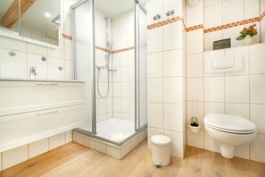 A modern bathroom with a glass-enclosed shower, a toilet, and a sink with a mirror. - Enjoy the cozy Klaas vacation apartment at Trollhüs in Norddorf on Amrum (Norddorf auf Amrum)