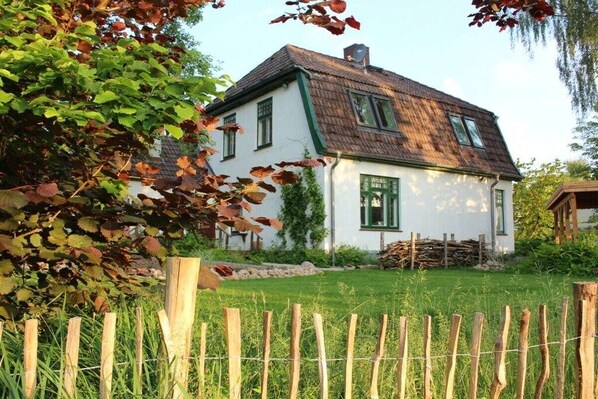 Een wit huis met een groen dak en een houten hek op de voorgrond.
