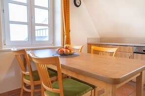 En matplats med ett träbord, fyra stolar och en fruktskål.