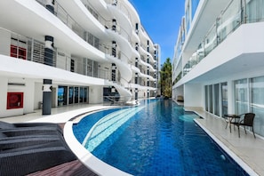 Un hotel moderno con piscina central, varios balcones y un diseño limpio y contemporáneo.