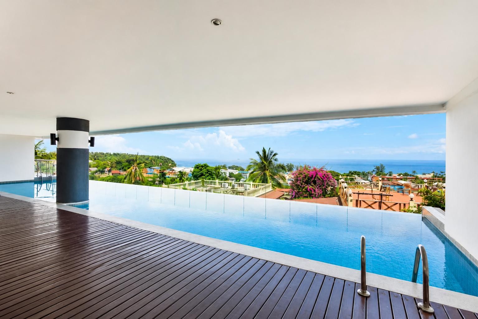 Una piscina infinita con vistas al océano y una terraza de madera.