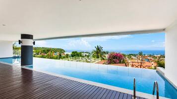 Una piscina infinita con vistas al océano y una terraza de madera.
