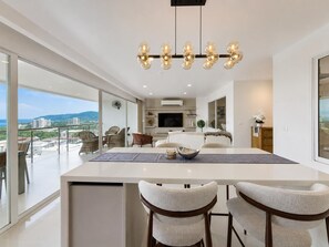 Una cucina moderna con isola centrale, zona pranzo con due sedie e un'ampia finestra che offre vista sulla città.