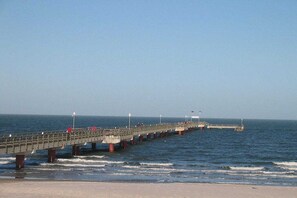 Een steiger die zich uitstrekt in de zee, met een heldere lucht erboven.